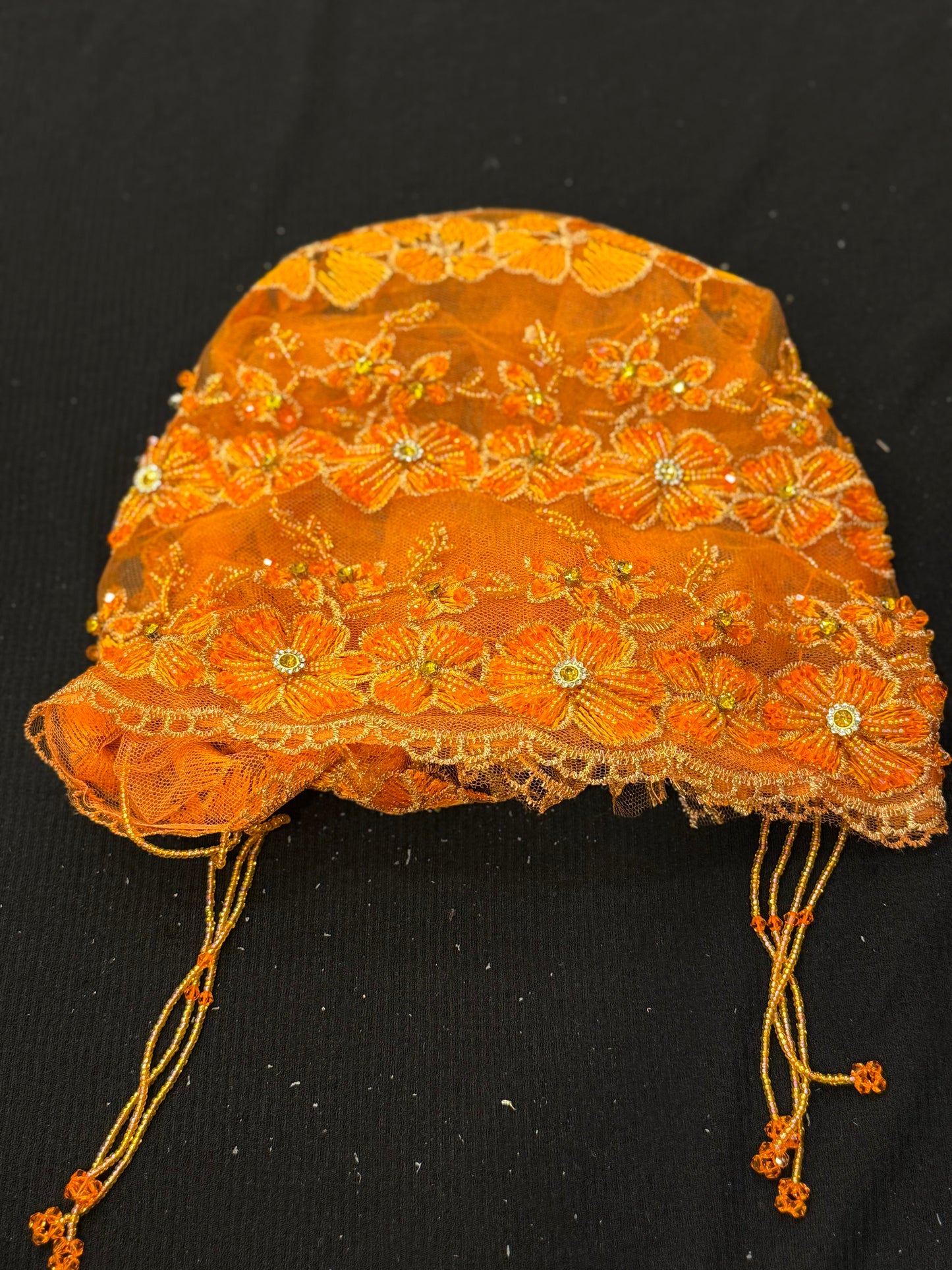 Orange lace hijab cap flat lay with embellished floral pattern