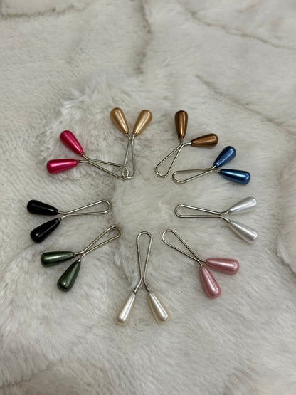 Multicolor pearl drop hijab pins set arranged in circle on white fur background