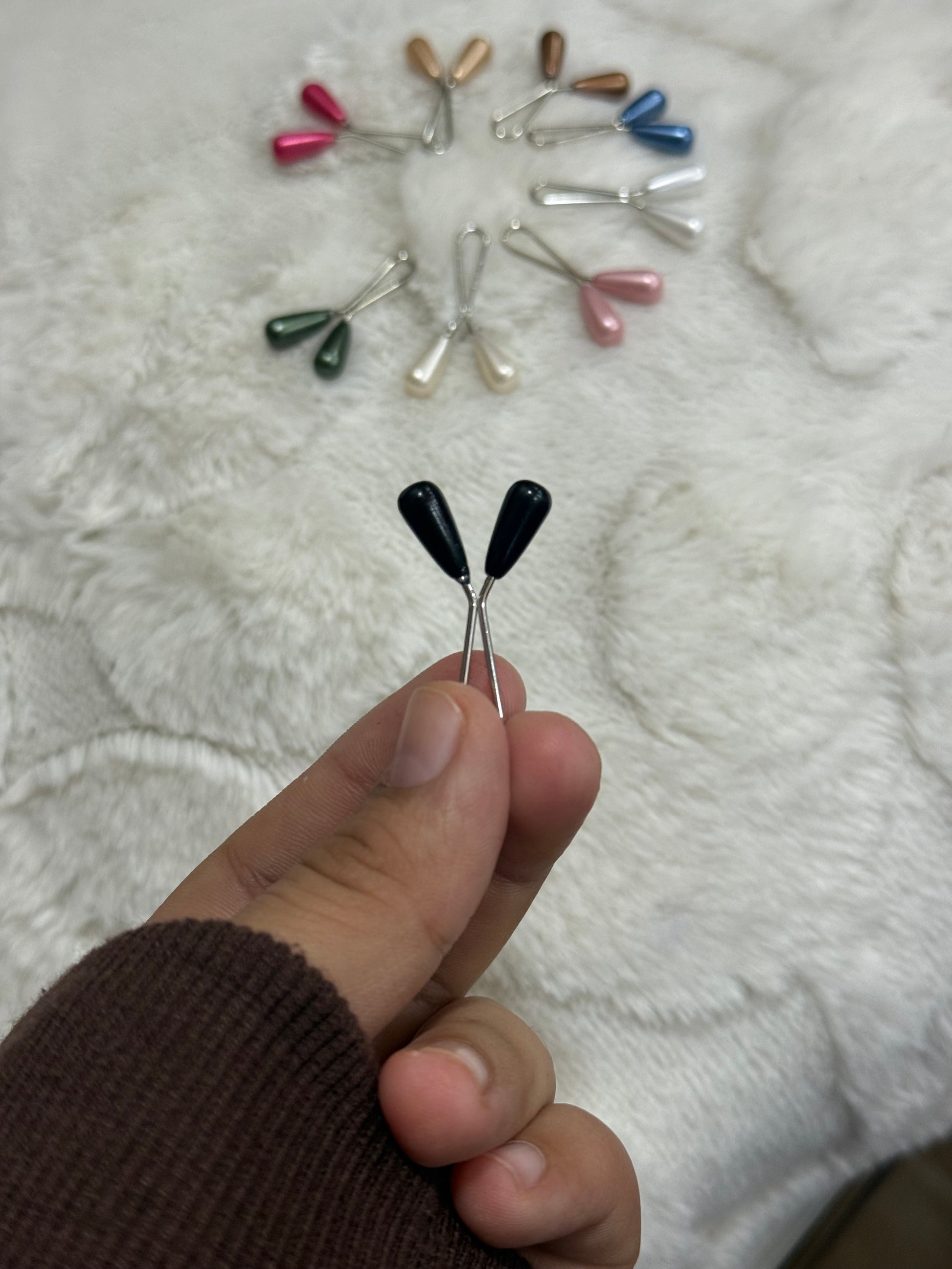 Decorative pearl drop hijab pins in multiple colors on fluffy white surface